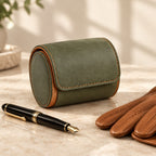 Green 1-slot watch roll closed, beside a fountain pen and leather gloves