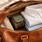 1-slot watch roll packed in a weekender bag beside folded shirts