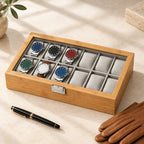 12-slot bamboo watch box closed, beside a fountain pen and leather gloves