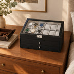 12-slot watch box with two drawers on a wooden dresser beside a valet tray and a book
