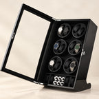 Black 12-watch winder cabinet with the glass door open and six watches