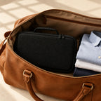 15-slot zippered hard-shell watch case packed in a leather weekender bag, for scale