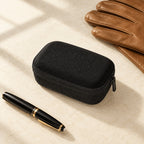 2-slot hard shell watch case closed, beside a fountain pen and leather gloves