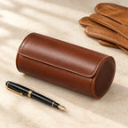 Brown 2-slot watch roll closed, beside a fountain pen and leather gloves