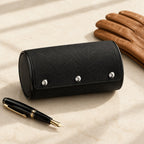 Black 2-watch roll closed, beside a fountain pen and leather gloves