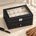 20-slot black faux leather watch box closed, beside a fountain pen and leather gloves