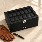 24-slot black watch box closed, beside a fountain pen and leather gloves