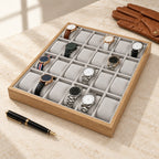 24-slot wooden watch tray beside a fountain pen and leather gloves