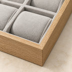 Close-up of the grey pillows and wood-grain frame of the watch tray