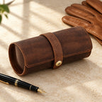 Cowhide leather watch roll closed, beside a fountain pen and leather gloves