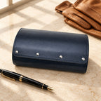 6-watch faux leather travel case closed, beside a fountain pen and leather gloves