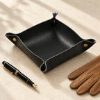 Empty black valet tray beside a fountain pen and leather gloves