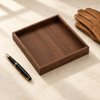 Empty black walnut valet tray beside a fountain pen and leather gloves