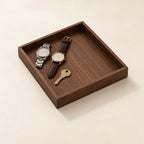 Square black walnut valet tray holding two watches and a key