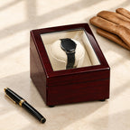 Burgundy watch winder beside a fountain pen and leather gloves