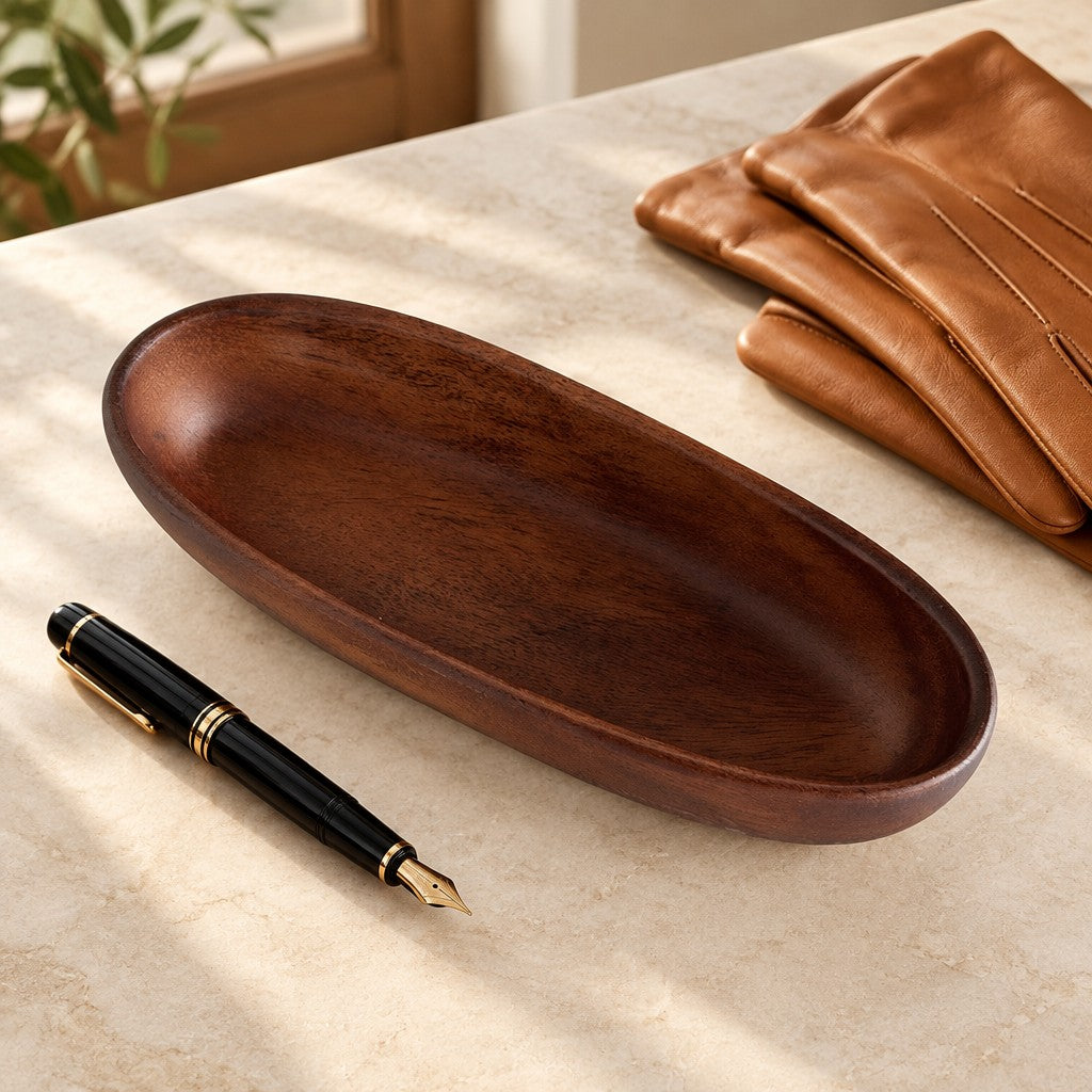 Carved walnut oval valet tray, beside a fountain pen and leather gloves