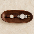 Carved walnut oval valet tray, from above, with watches of different sizes