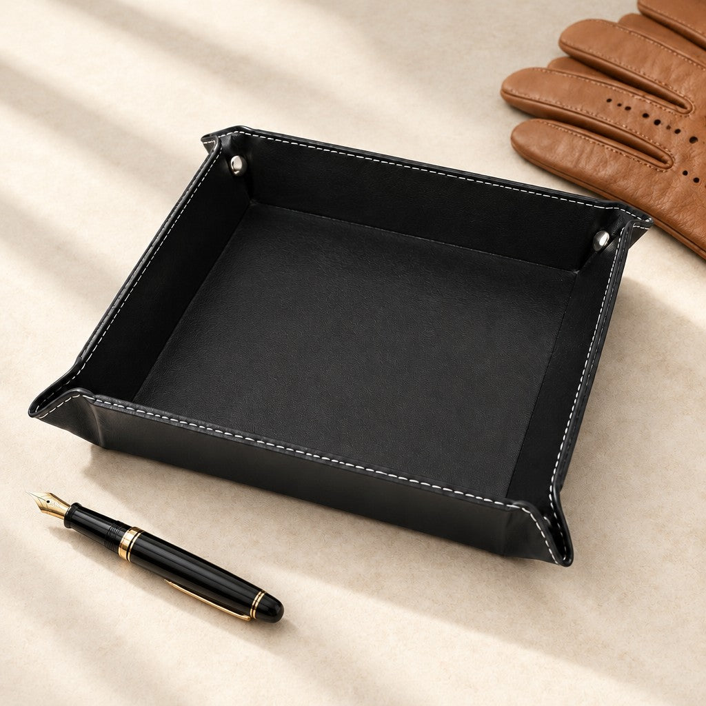 Empty black faux leather valet tray beside a fountain pen and leather gloves