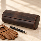 Crazy horse leather watch roll closed, beside a fountain pen and leather gloves