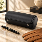 Black leather watch roll closed, beside a fountain pen and leather gloves