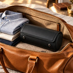 Closed leather watch roll packed in a weekender bag beside folded shirts