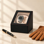 Carbon-fiber watch winder beside a fountain pen and leather gloves