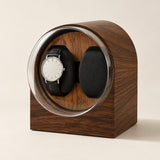 Double watch winder in dark wood grain with one watch on its pillow
