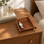 Foldable leather valet tray on a bedside chest of drawers, for scale