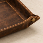 Close-up of the distressed cowhide leather, stitching and brass snap button