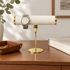 Gold-tone T-bar watch stand on a chest of drawers, for scale