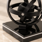 Close-up of the watch holder, a silver pivot screw and the gloss black base