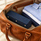 Hexagonal 3-slot watch case in navy with orange interior, in an open leather weekender bag