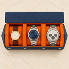 Hexagonal 3-slot watch case in navy with orange interior, from above, with watches of different sizes