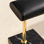 Close-up of the smooth black leather pillow and the gold stem on marble