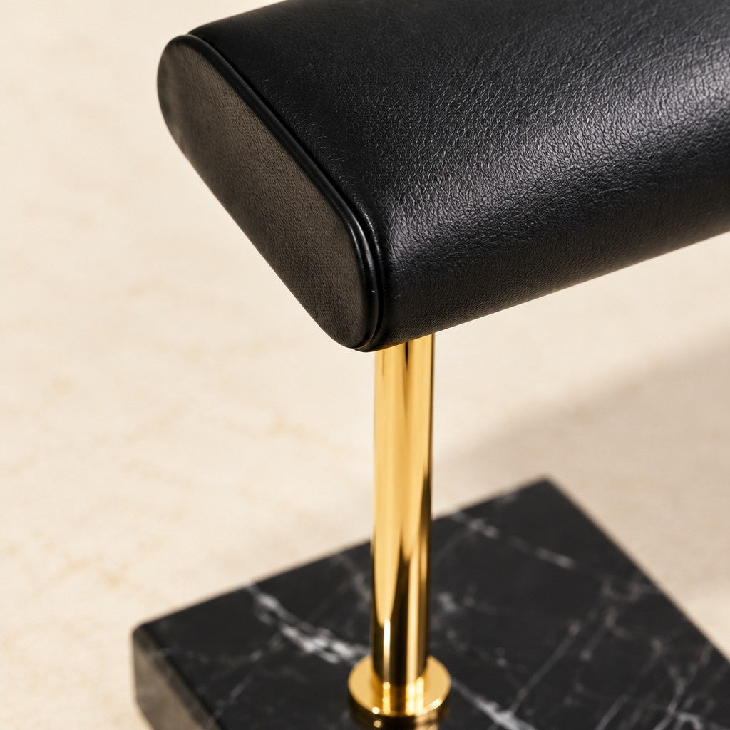 Close-up of the smooth black leather pillow and the gold stem on marble