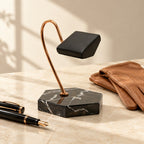 Black marble hook watch stand beside a fountain pen and leather gloves