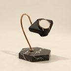 Black marble hook watch stand holding a watch on a black cushion
