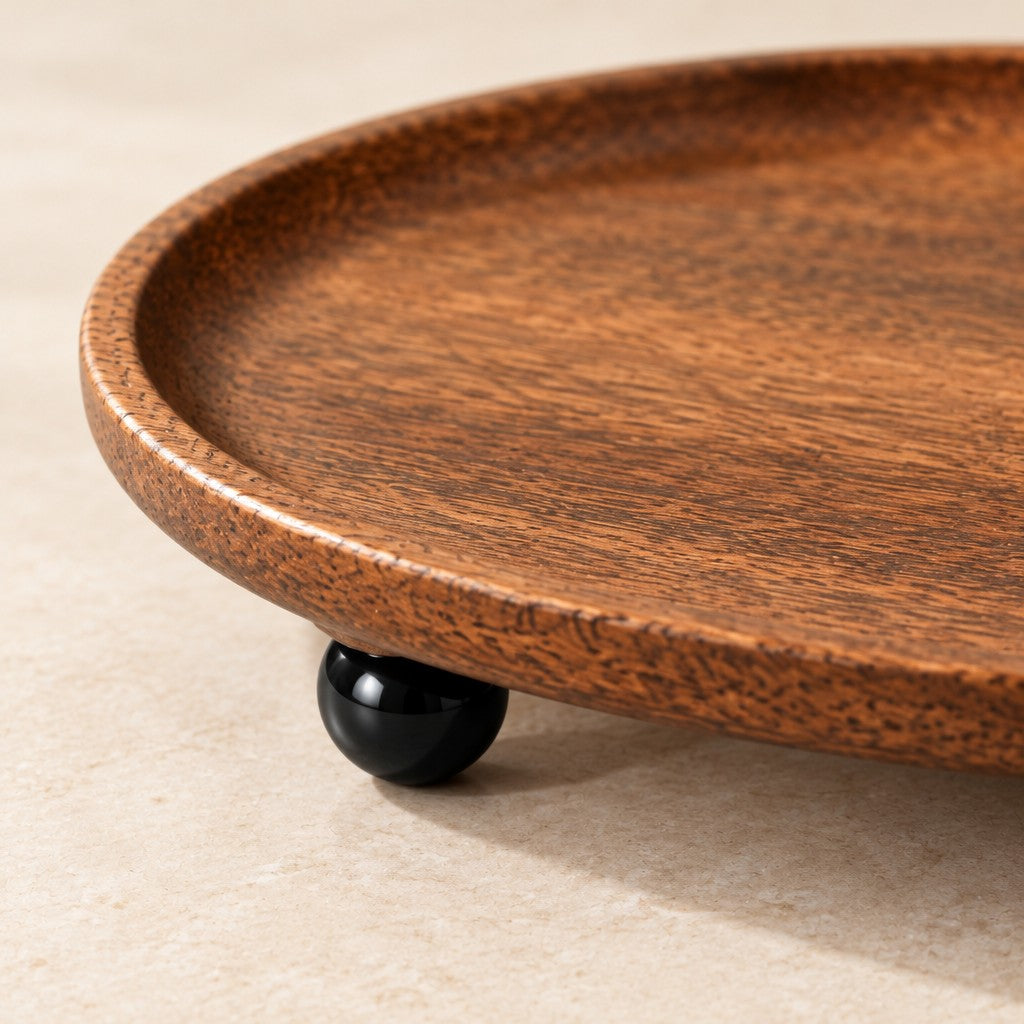 Close-up of the wood grain, rim and a black ball foot of the catchall tray