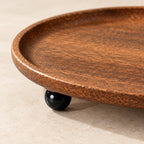 Close-up of the wood grain, rim and a black ball foot of the catchall tray
