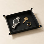 Pebbled leather valet tray with a watch, three-quarter view