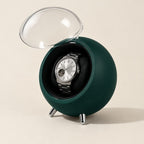 Dark green round watch winder with the clear dome open and a watch on the pillow