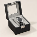 Single watch box in black faux leather with a glass window, open with one watch
