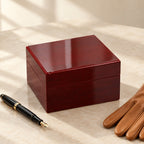 Red lacquered single watch box closed, beside a fountain pen and leather gloves