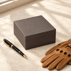 Single watch presentation box closed, beside a fountain pen and leather gloves