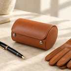 Cognac single watch roll closed, beside a fountain pen and leather gloves