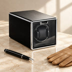 Single watch winder beside a fountain pen and leather gloves