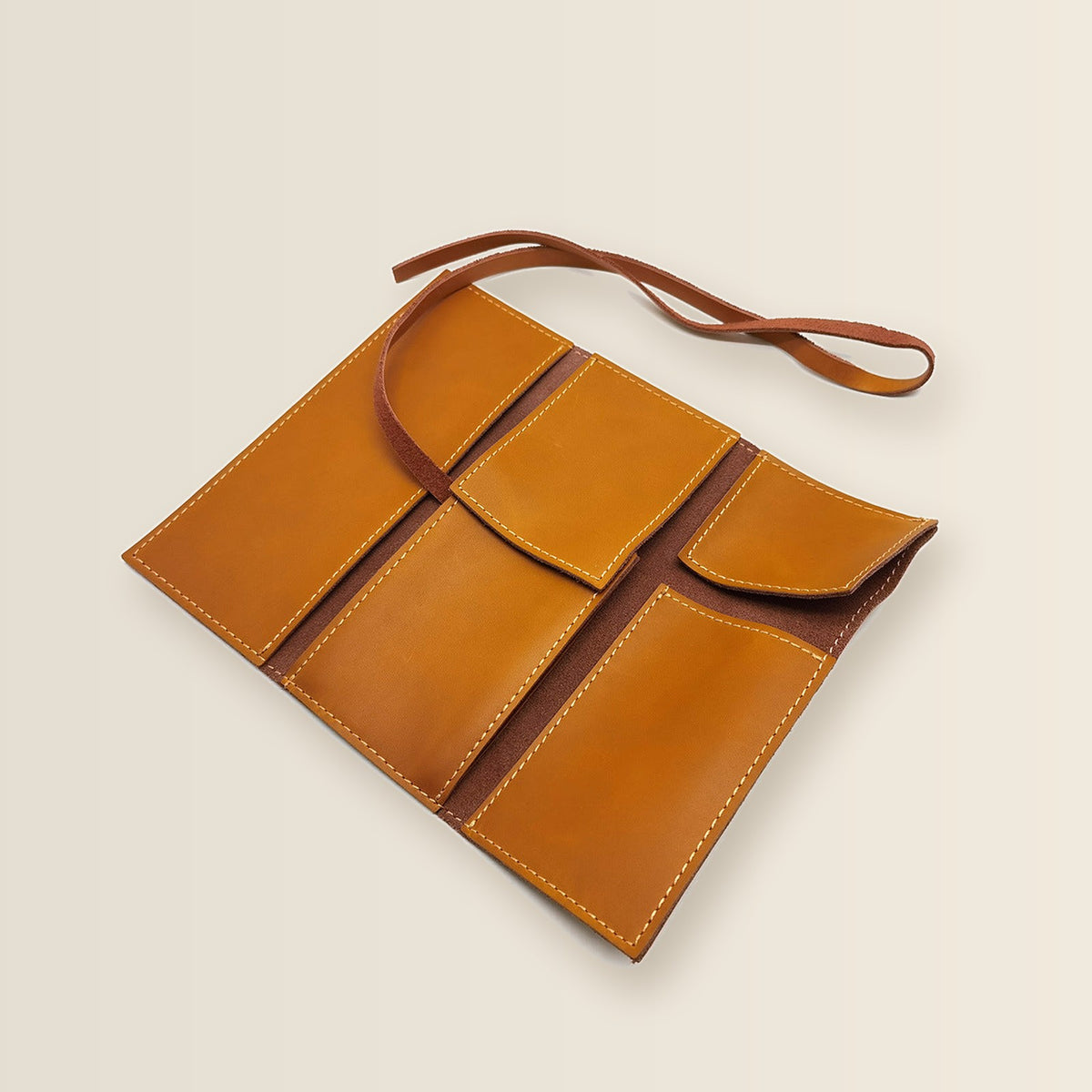 Tan leather watch roll opened flat, showing its pockets and flaps