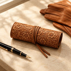 Tooled cowhide leather watch roll with 4 pockets, beside a fountain pen and leather gloves