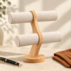 Curved wooden watch stand beside a fountain pen and leather gloves