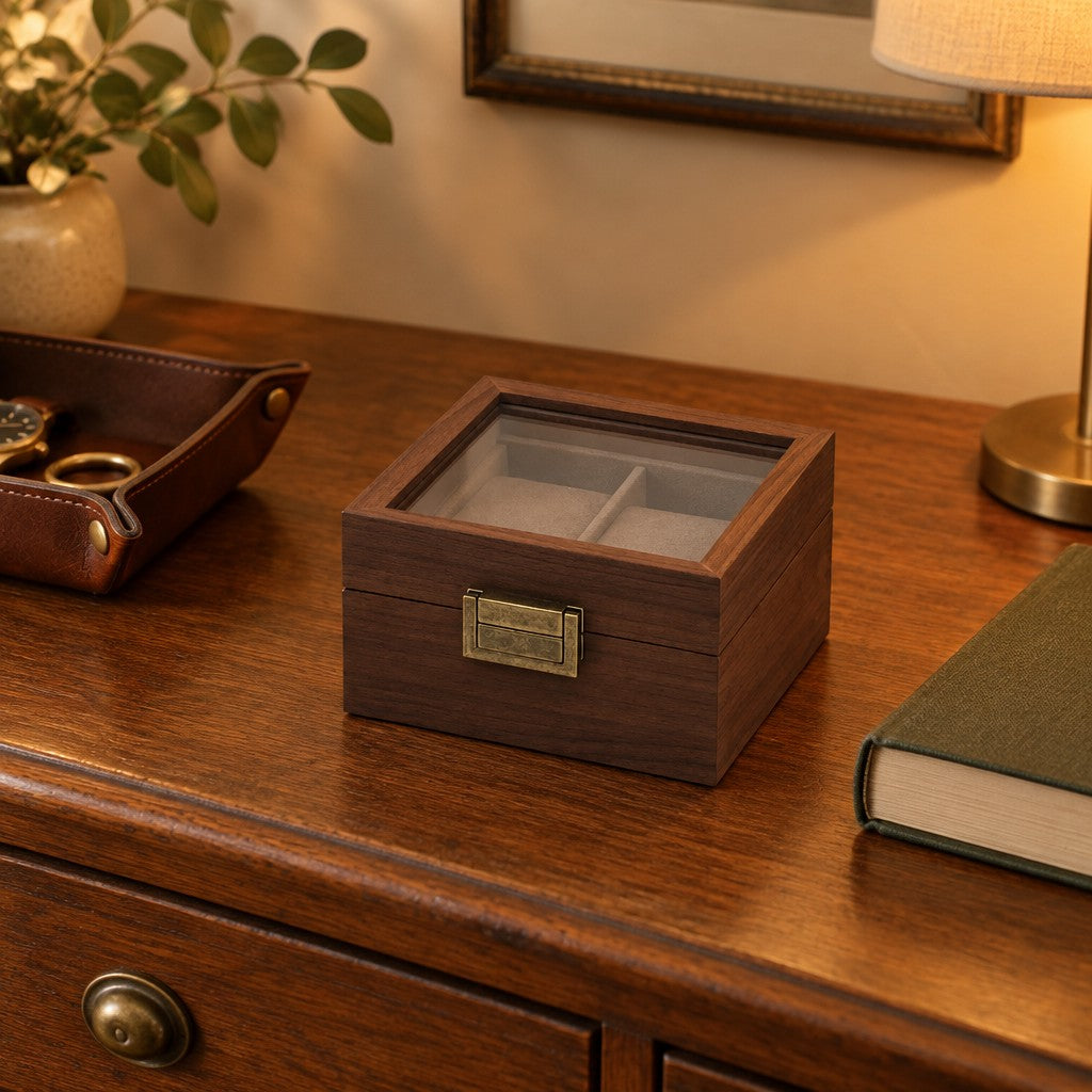 Walnut watch box on a chest of drawers, beside a leather tray and a book